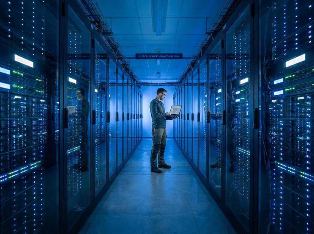Sysadmin managing dedicated server rental hardware in a modern data center aisle.