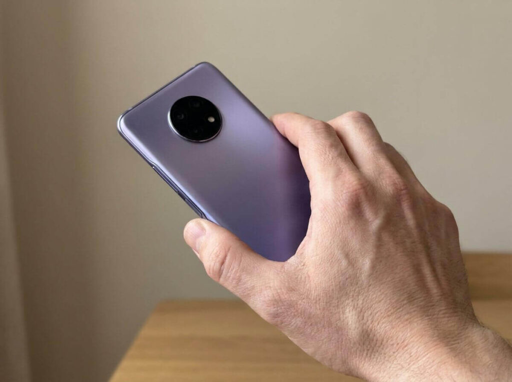 Large vivo V70 FE phone held in one hand showing its curved purple design